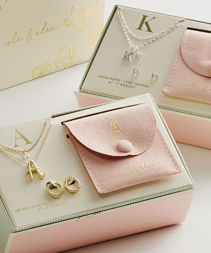 Personalized necklaces displaying an 'A' and a 'K' displayed with matching earrings in a gift box.