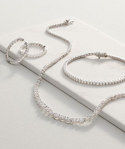 2 necklaces and 2 bracelets draped over gray display padding.