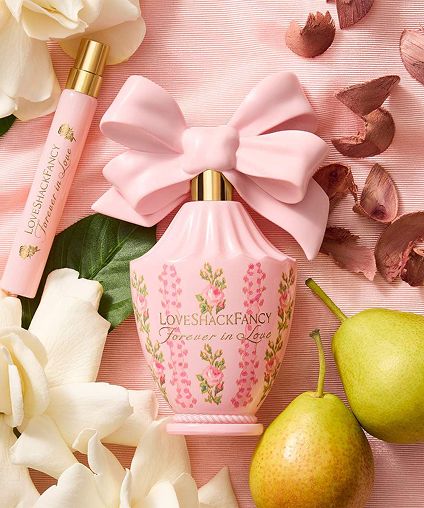 LoveShackFancy products on top of flowers and fruits on a pink background.