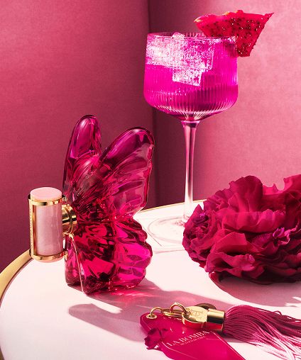 Various pink and red products arranged on a table in front of a glass filled with pink liquid.