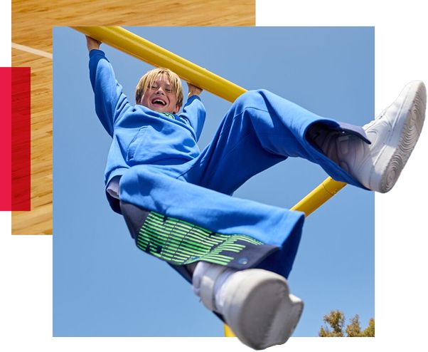 Little boy hanging from playground railing.
