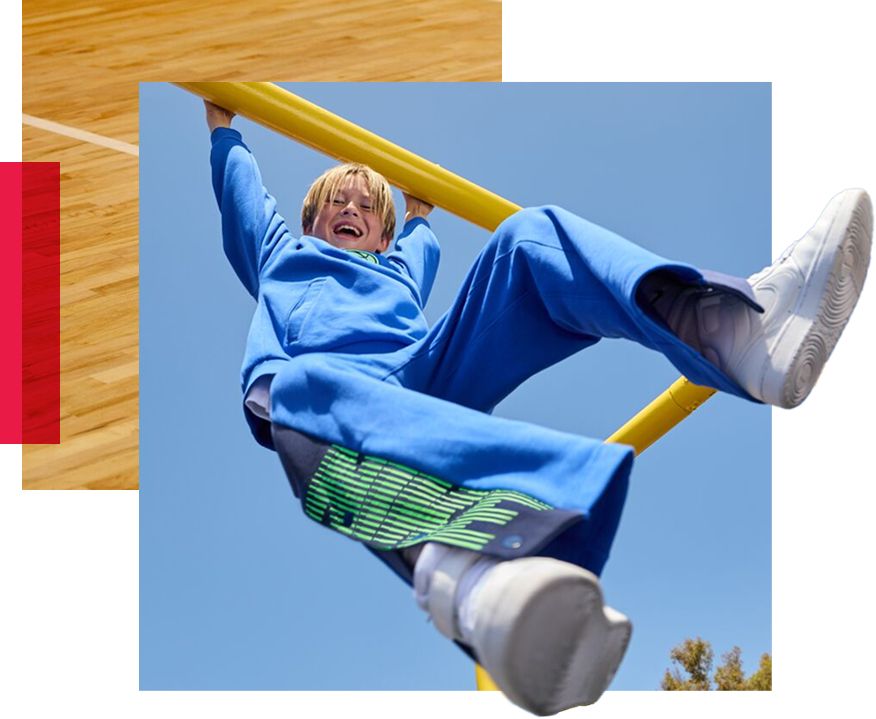 Little boy hanging from playground railing.