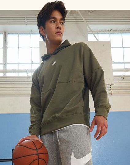 Teen in hoodie holding basketball.