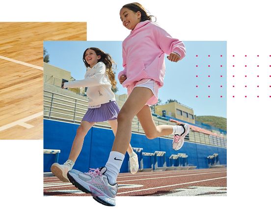 Two girls running on a track. Three backpacks stacked.