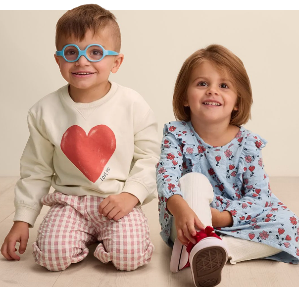 Two children wearing various Little Co gear smiling for the camera.