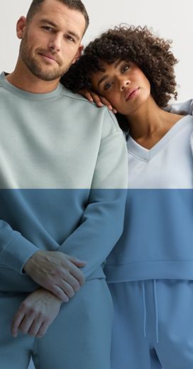 2 people. man wearing a light green long sleeve shirt. woman wearing light blue shirt with similarly colored clothing hung over her shoulder. She rests her head on the mans shoulder.
