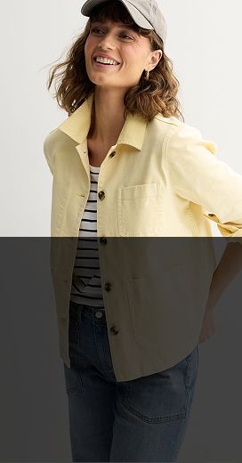 woman wearing a grey baseball cap and a black and white striped shirt with a yellow unbuttoned shirt over the top with sleeve rolled to elbow