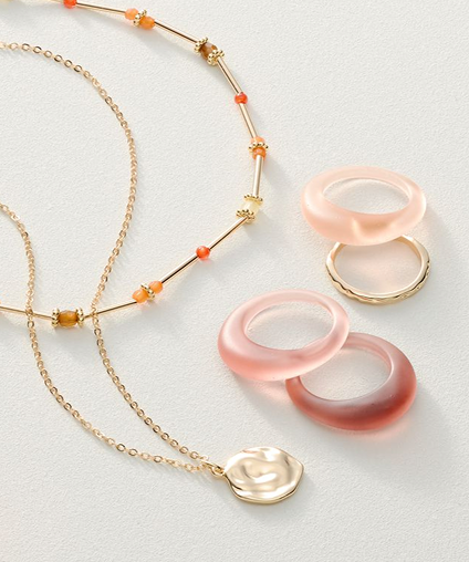 Various rings and necklaces laid out on a gray background.