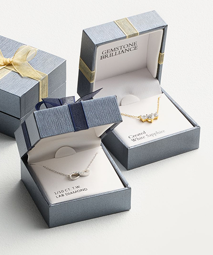 3 small jewelry boxes. Two of them opened to reveal necklaces.