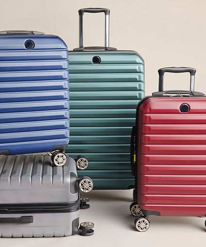 Four pieces of DELSEY PARIS luggage - gray, blue, green, and red.