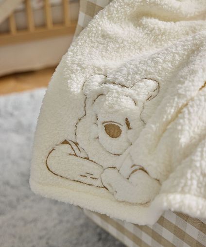 Soft white blanket with a character design on it in brown.