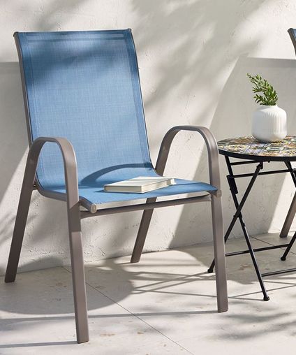 Patio chair outside next to a small fold out table with a flower pot.