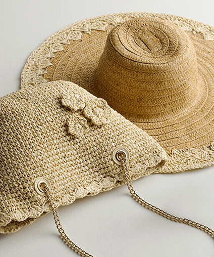 A straw bag draped on top of a straw hat.