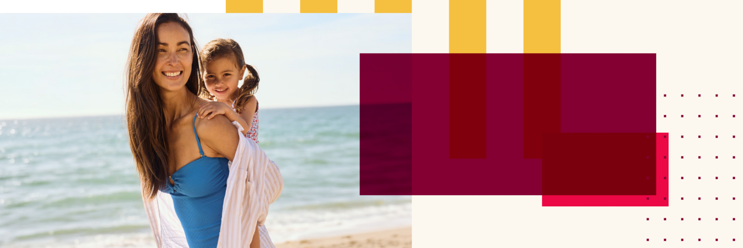 Woman carriying a child on her back at the beach as both smile.