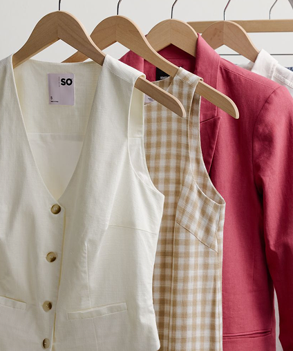 Woman holding a bag in a casual stance while wearing a linen overshirt and pants.