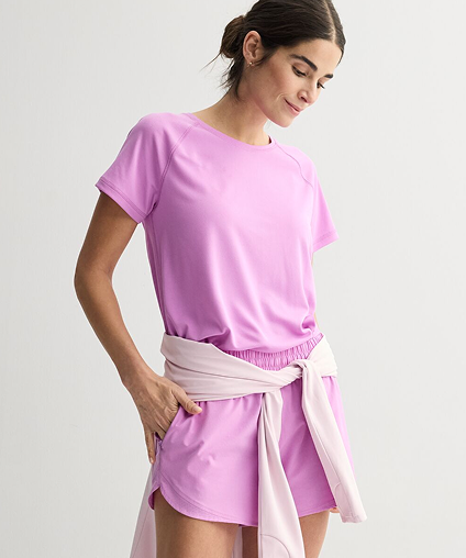 Womena in a purple dress with a pink sweater tied around the waist.