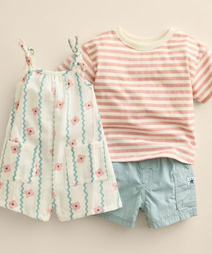 Shirt and shorts and onesie outfits laid out on a beige background.