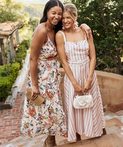 Two womens in dresses embracing at the top of a stairway.
