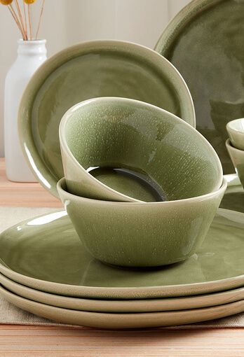 Green bowls on top of a stack of plates of the same color.