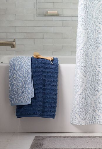 Bathroom with a view of two towels draped on the edge of a bath tub.