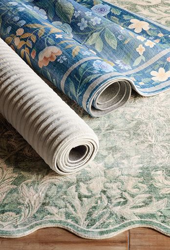 Two rugs of various colors rolled up on top of a green and white rug.