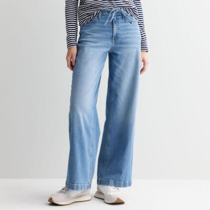 Model wearing jeans, a striped shirt, and white sneakers.