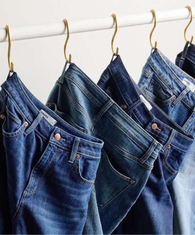 Rack with various styles of denim pants hanging off it.