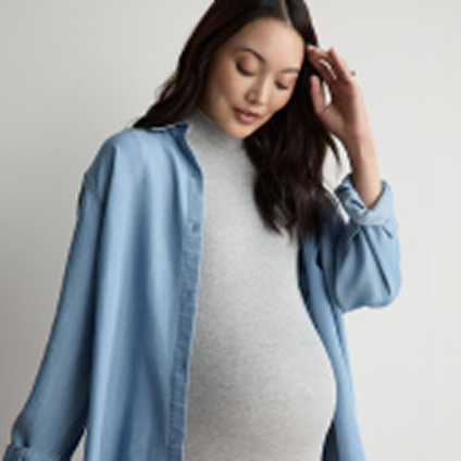 Model wearing an unbuttoned blue shirt over a gray maternity shirt.