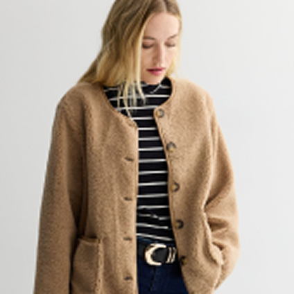 Model wearing a light brown jacket over a black and white striped shirt.