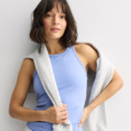 Model wearing a blue activewear top with a sweatshirt draped over the shoulders.