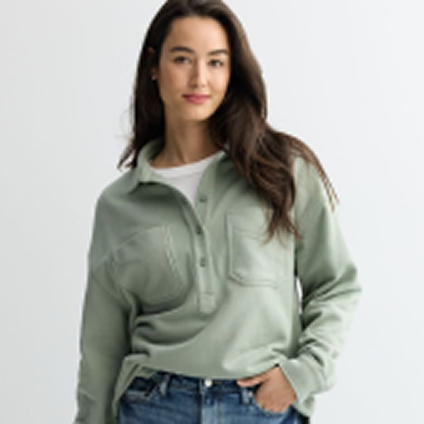 Model with a green top and denim pants, hand in pocket.