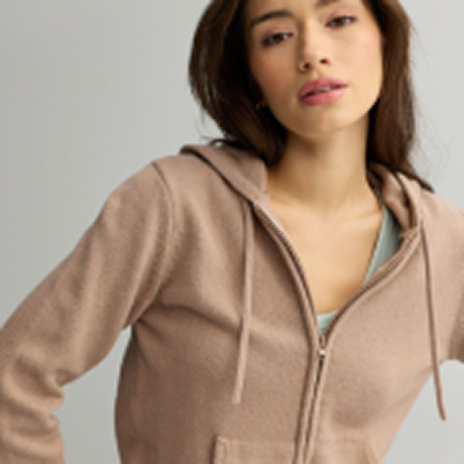 Model wearing a light brown hoodie with a blue tank top underneath.