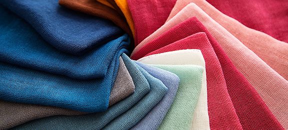 Folded fabrics in shades of blue, pink, red, and mint green.