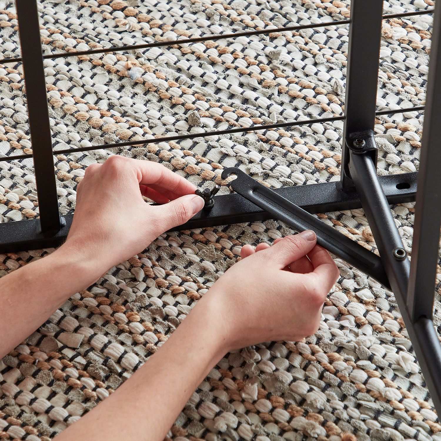 Hand adjusting/handling black metal platform bed frame supports