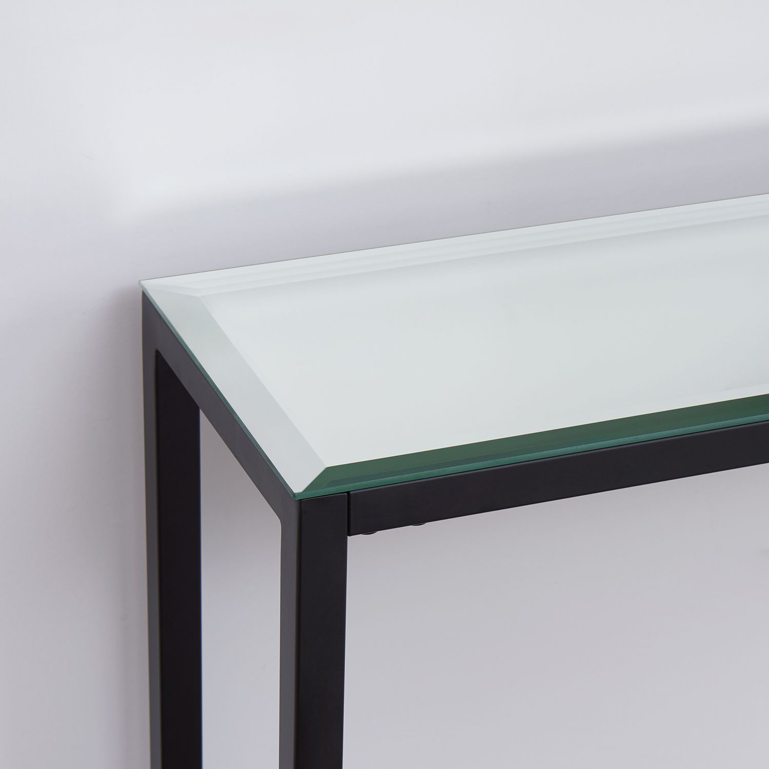 Close-up of glass tabletop edge on black metal console table