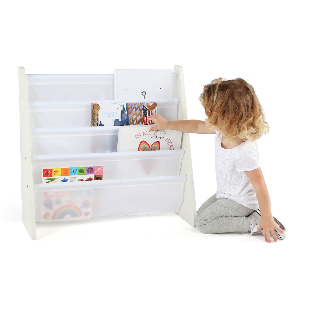 Child organizing books in a white 4-pocket wood book rack.