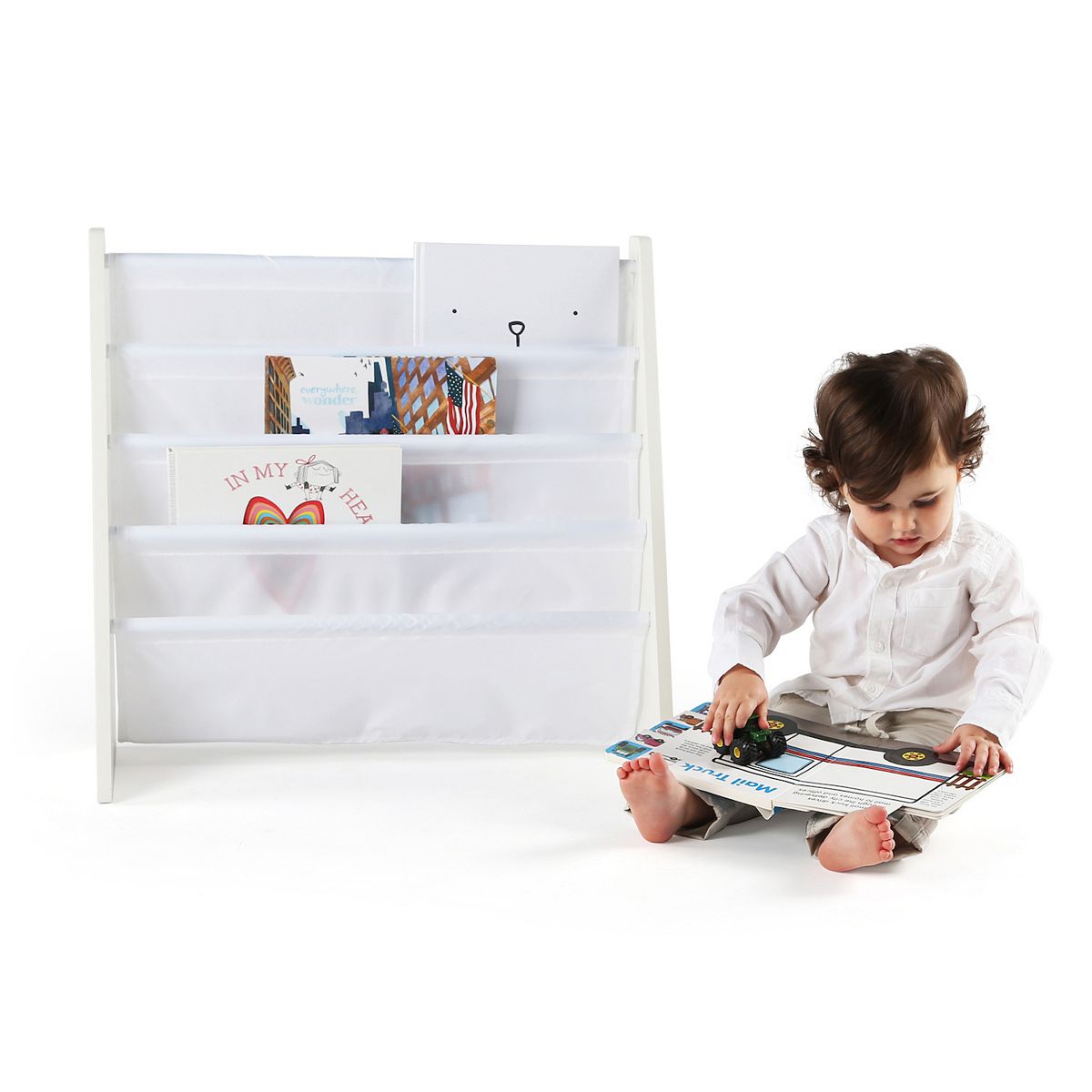 Child reading beside a white 4-pocket wood book rack with books inside.