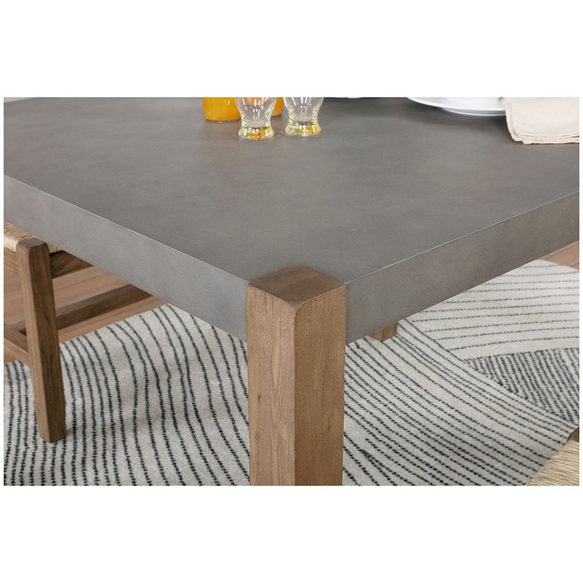 Corner of gray dining table with light wood leg and rounded edges