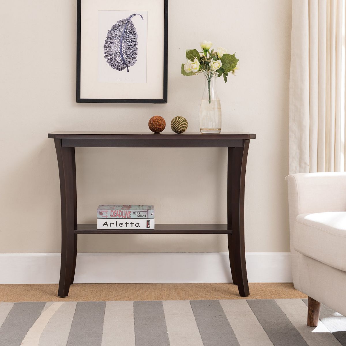Console hall stand with shelf styled with décor against a wall.