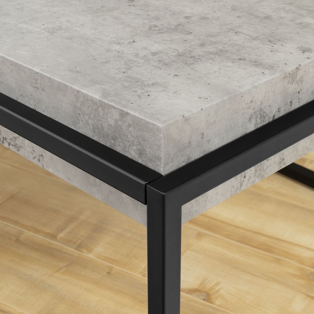 Corner close-up of concrete-look top and black frame on coffee table