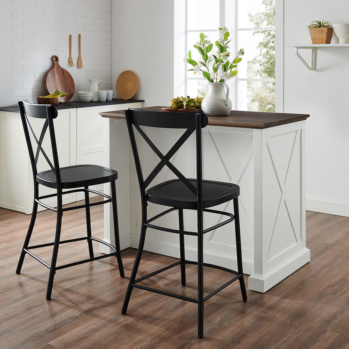 White kitchen island with two black stools in front of white cabinetry