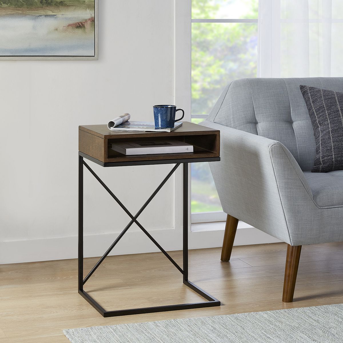 End table next to sofa with magazine and mug on top