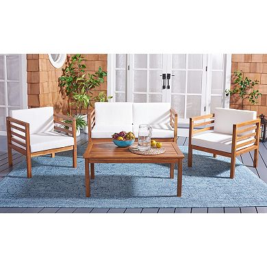 Four white cushioned wooden patio chairs around a wooden coffee table on blue rug