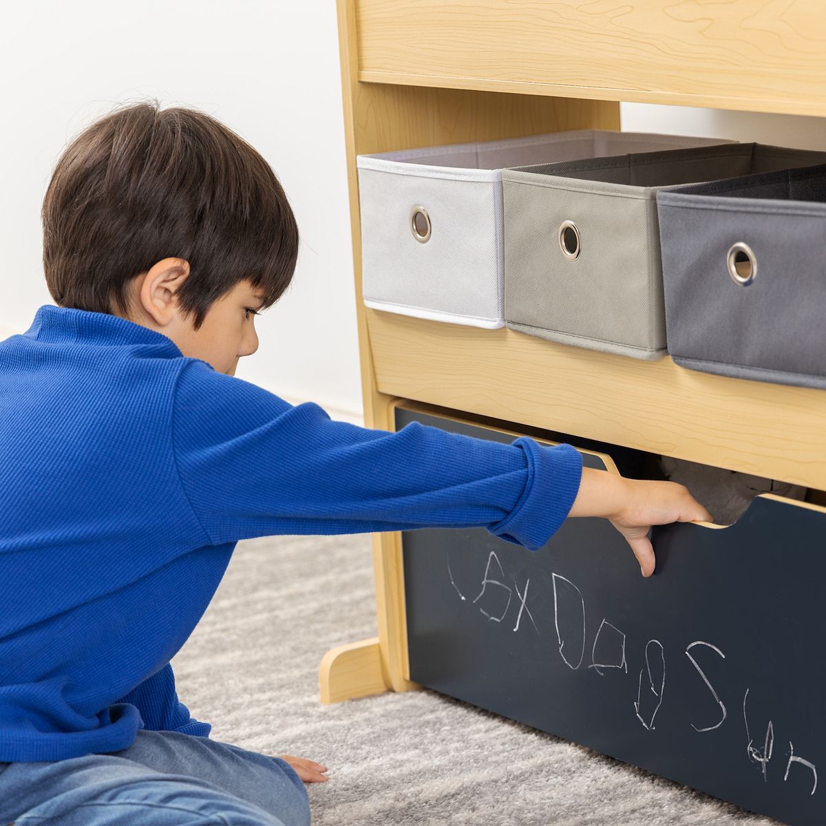 Child reaching into Humble Crew storage cabinet bins and navy drawer