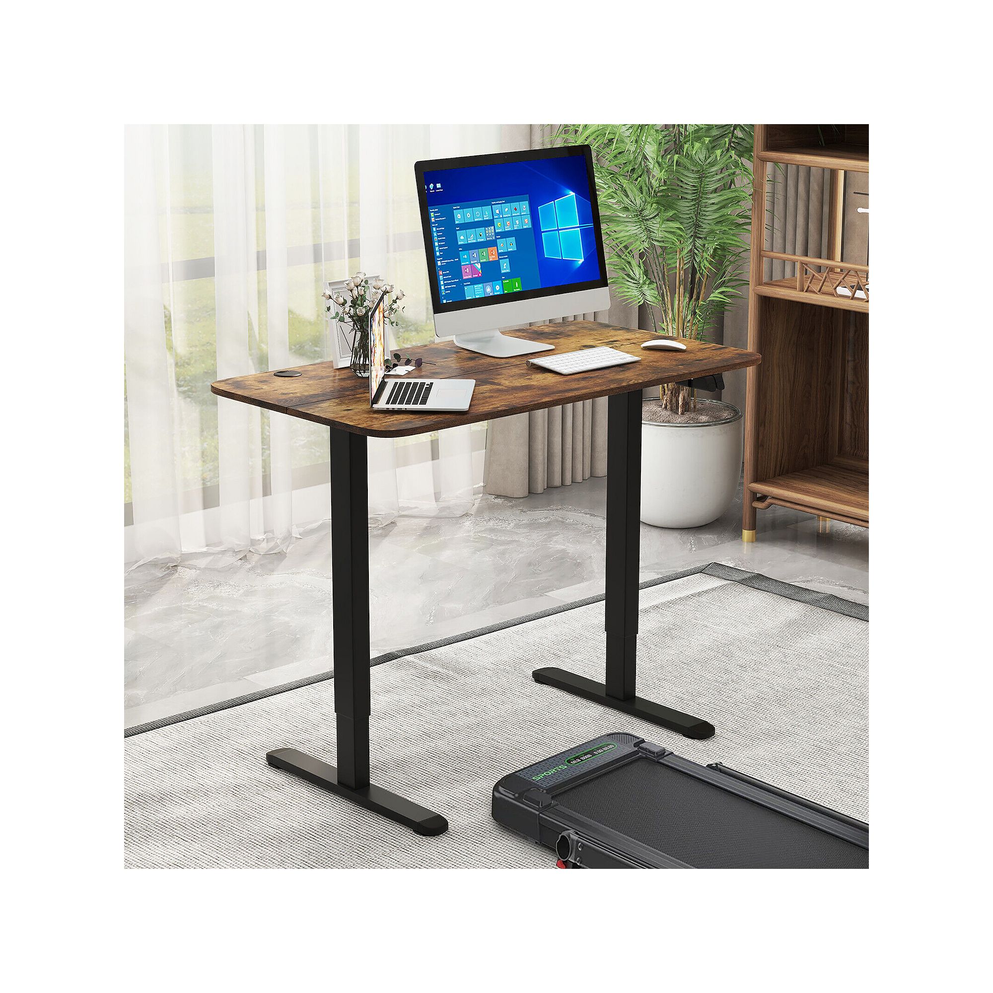 Electric standing desk with dark frame and wood top on floor