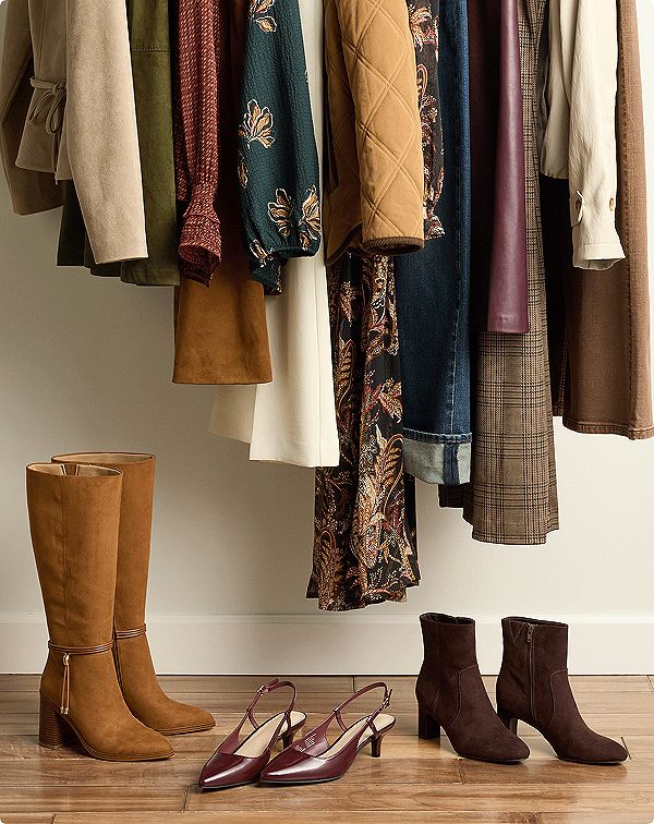 Clothesrack of warm-toned jackets, tops, and dresses with boots and footwear beneath