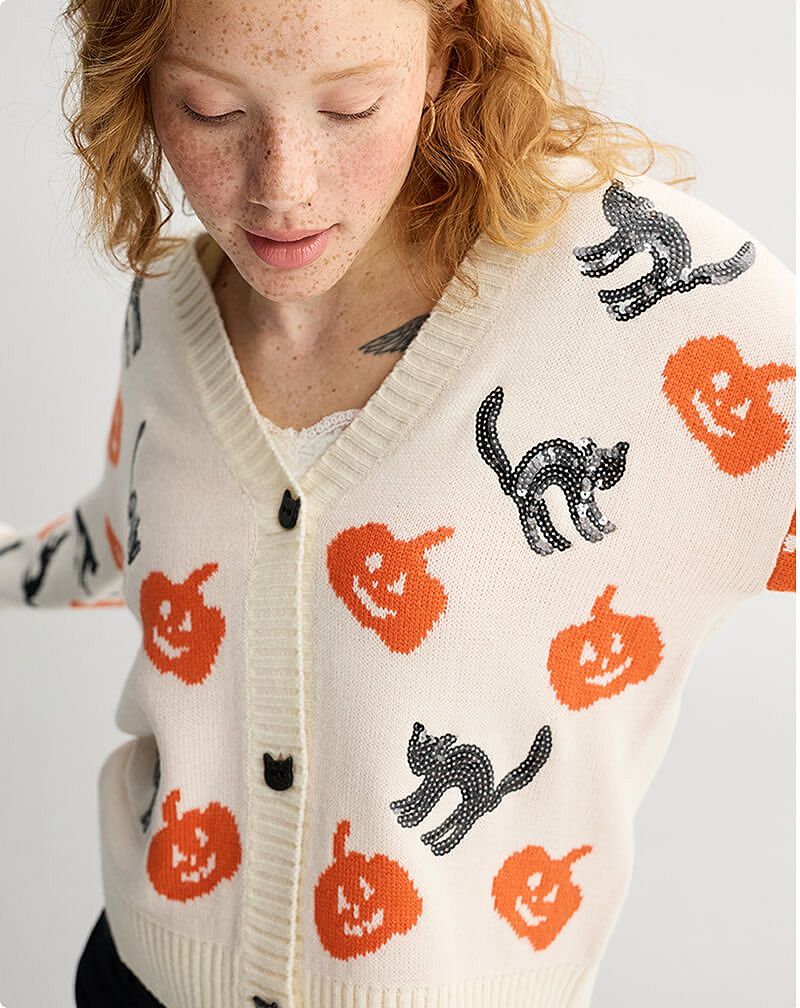 Woman wearing cream knit sweater with pumpkin decorations